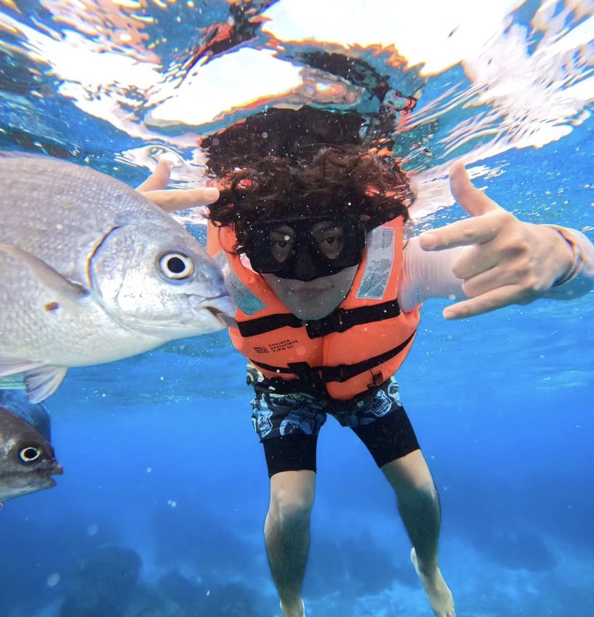 First aid kit and sunscreen beside snorkel gear on a tropical beach safety checklist